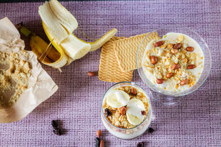 Delicious and healthy yogurt dessert with banana, biscuits and nuts.の写真素材