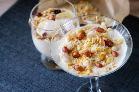 Delicious and healthy yogurt dessert with banana, biscuits and nuts.の写真素材