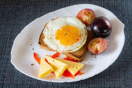 Delicious and healthy breakfast. Scrambled eggs on a toaster with cheese and tomatoes.の写真素材