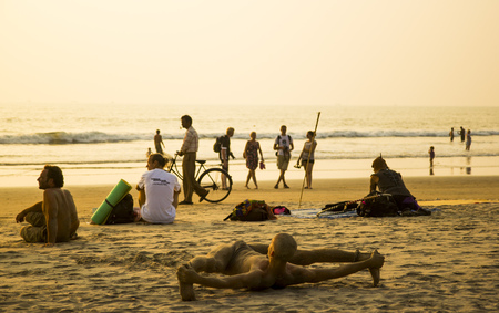 ARAMBOL BEACH, GOA, INDIA - FEBRUARY 15, 2013 - People are relaxing on beach, a man doing split.のeditorial素材