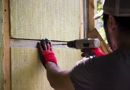 A man warming his house using mineral wool and drill, building a houseの写真素材