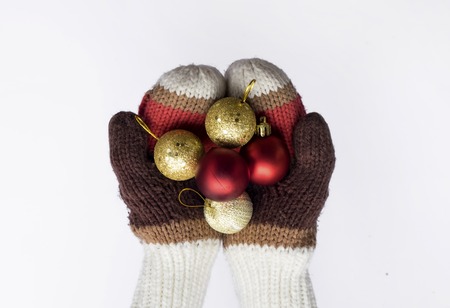 hands in knitted mittens with christmas balls isolated on white background.の写真素材