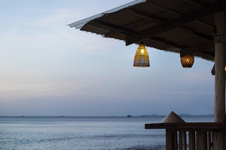 cozy cafe with bamboo lamps and Vietnamese conical hat on the sea backgroundの写真素材