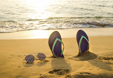 flip-flop and sunglasses on the beach at the sunset