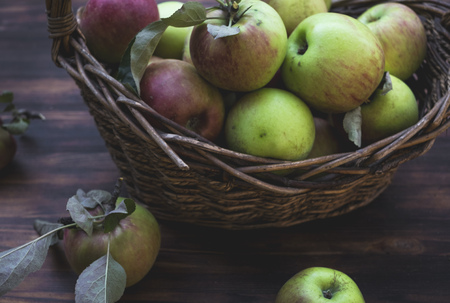 Red and green apples in basket on wooden tableの写真素材