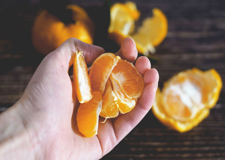 fresh ripe tangarine in the hand on the wooden background.の写真素材