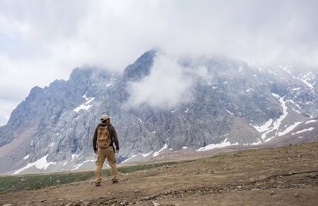 Rear view of man standing at the foot of impressive mountain. Kazakhstan, Almaty.の写真素材