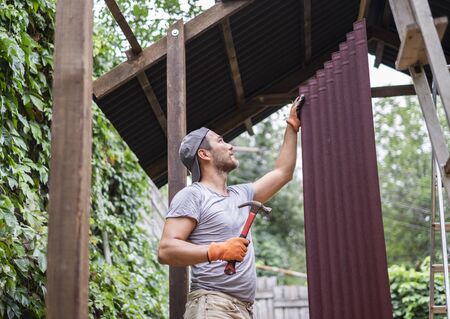 Man building roof and holding hammer and roof material.の写真素材