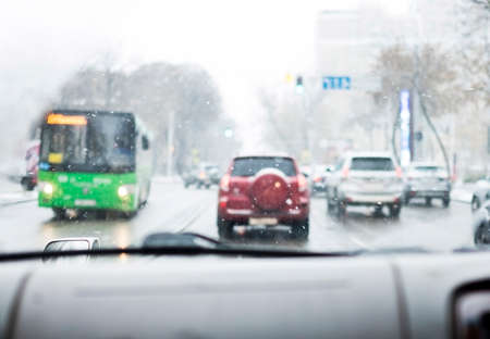 Driving around city during snowfall. View through windshield of car.の写真素材