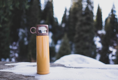 Yellow flask on wooden table in winter outdoorの写真素材