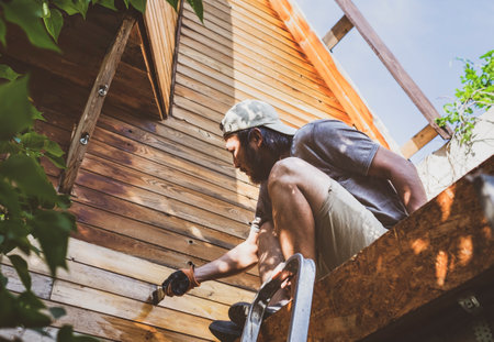Man painting wooden wall of house outdoorsの写真素材
