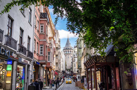 Istanbul, Turkey - November, 11, 2020: Galata Tower and a narrow vintage street with a yellow taxi.のeditorial素材