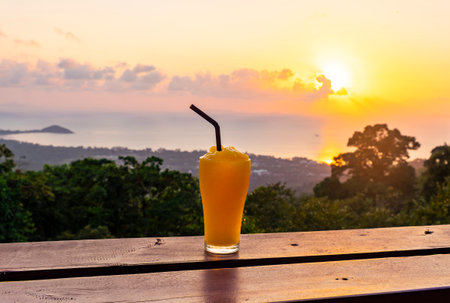 Mango smoothie on the background of beautiful sunset and sea from the view point in Koh Samui Island, Thailand.の写真素材