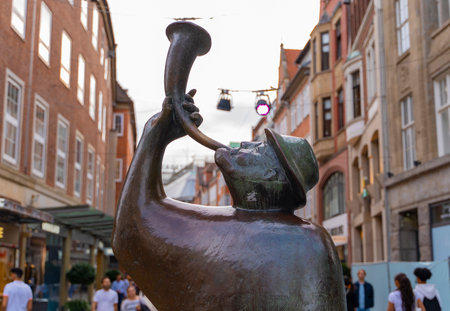 A bronze statue of a man blowing a horn located on a busy pedestrian street in Bremen, Germany. The...