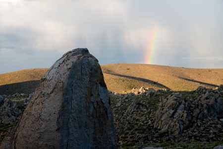 Rainbow over rocky hillsideの写真素材