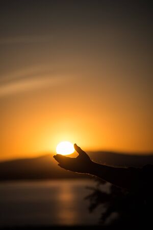 Man holding sun at sunrise at mono lakeの写真素材