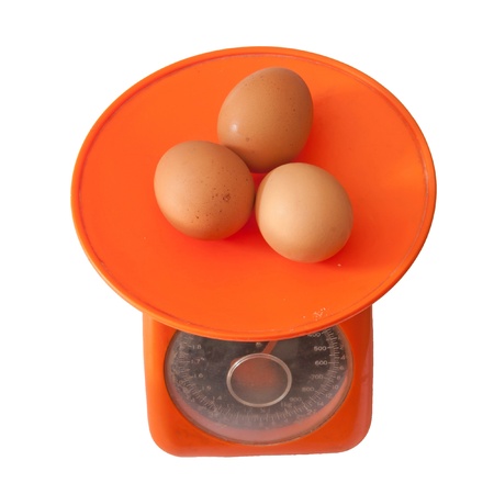 brown eggs on kitchen-scales isolated on white background