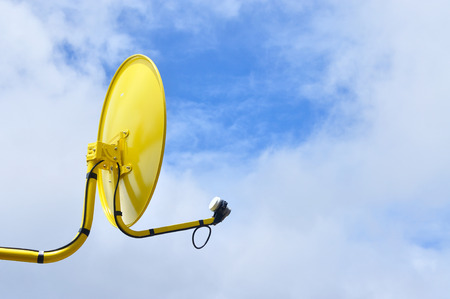 Yellow satellite dish for television with blue skyの写真素材