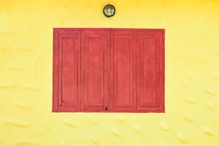 Red grunge wooden window on yellow wall