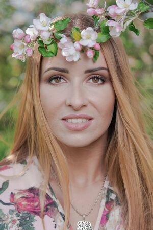 Blond girl with long hair in spring blooming apple orchardの写真素材