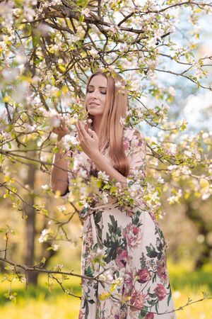 Blond girl with long hair in spring blooming apple orchardの写真素材