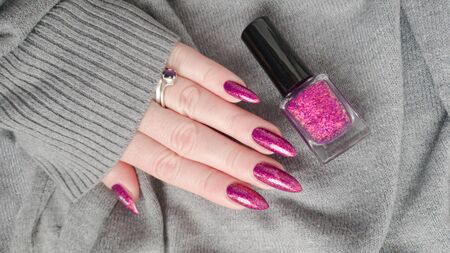 Female hand with long nails and pink fuchsia bottle manicure with nail polishの写真素材