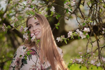 Blond girl with long hair in spring blooming apple orchardの写真素材