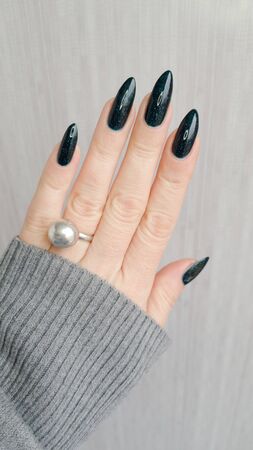 Female hand with long nails and blue manicure with bottles of nail polishの写真素材