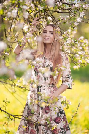 Blond girl with long hair in spring blooming apple orchardの写真素材