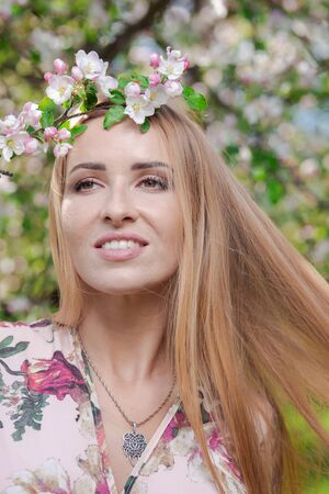 Blond girl with long hair in spring blooming apple orchardの写真素材