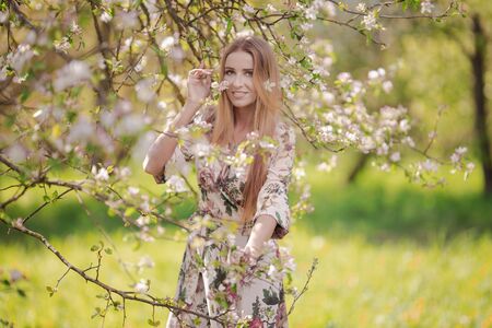 Blond girl with long hair in spring blooming apple orchardの写真素材