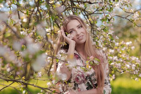Blond girl with long hair in spring blooming apple orchardの写真素材