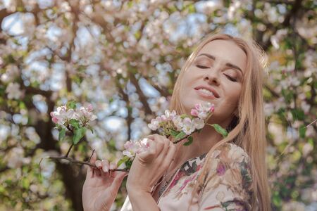Blond girl with long hair in spring blooming apple orchardの写真素材