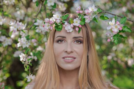 Blond girl with long hair in spring blooming apple orchardの写真素材