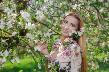 Blond girl with long hair in spring blooming apple orchard