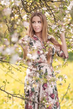 Blond girl with long hair in spring blooming apple orchardの写真素材