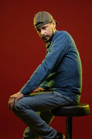 Brunette man with a beard posing on a red background in the studioの写真素材
