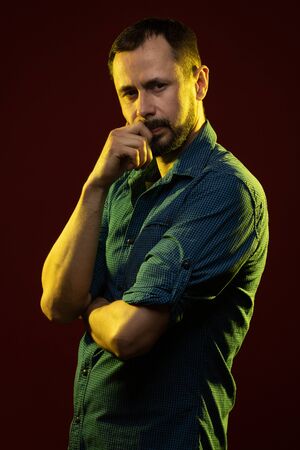 Brunette man with a beard posing on a red background in the studioの写真素材