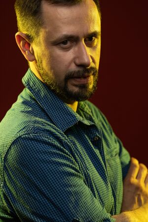 Brunette man with a beard posing on a red background in the studioの写真素材