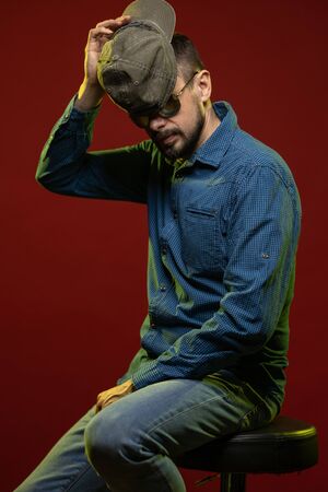 Brunette man with a beard posing on a red background in the studioの写真素材