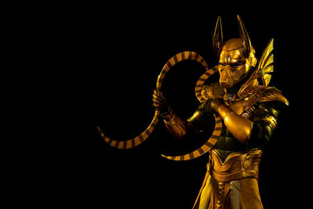 a male actor in a suit of an Egyptian mythology character, the golden deity Jackal Anubis, twists...
