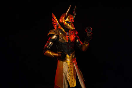 a male actor in a suit of an Egyptian mythology character, the golden deity Jackal Anubis, twists buugeng in red light on a black backgroundの写真素材