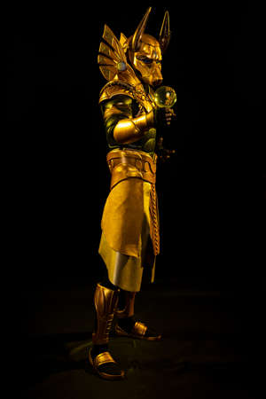 a male actor in a suit of an Egyptian mythology character, the golden deity Jackal Anubis, twists...