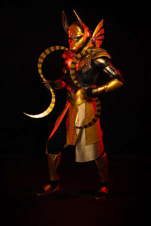 a male actor in a suit of an Egyptian mythology character, the golden deity Jackal Anubis, twists...