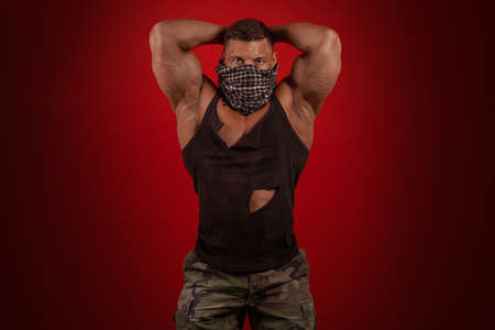 Young male athlete bodybuilder posing on a red background