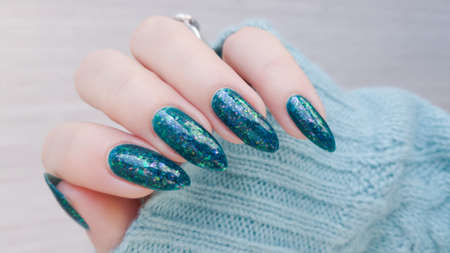 Female hand with long nails and blue sea color manicure with bottles of nail polishの写真素材