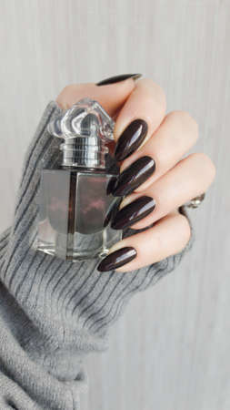 Female hand with long nails and black manicure with bottles of nail polish