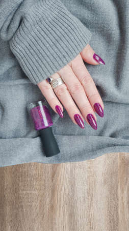 Woman hand with long nails manicure and pink fuchsia bottle with nail polishの写真素材