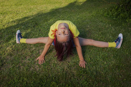 Brunette girl dancing, jumping, doing acrobatics and posing, in a city park near the lake on a sunny...