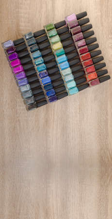 Background for design. A large number of multi-colored bottles with nail polishes laid out on the tableの写真素材